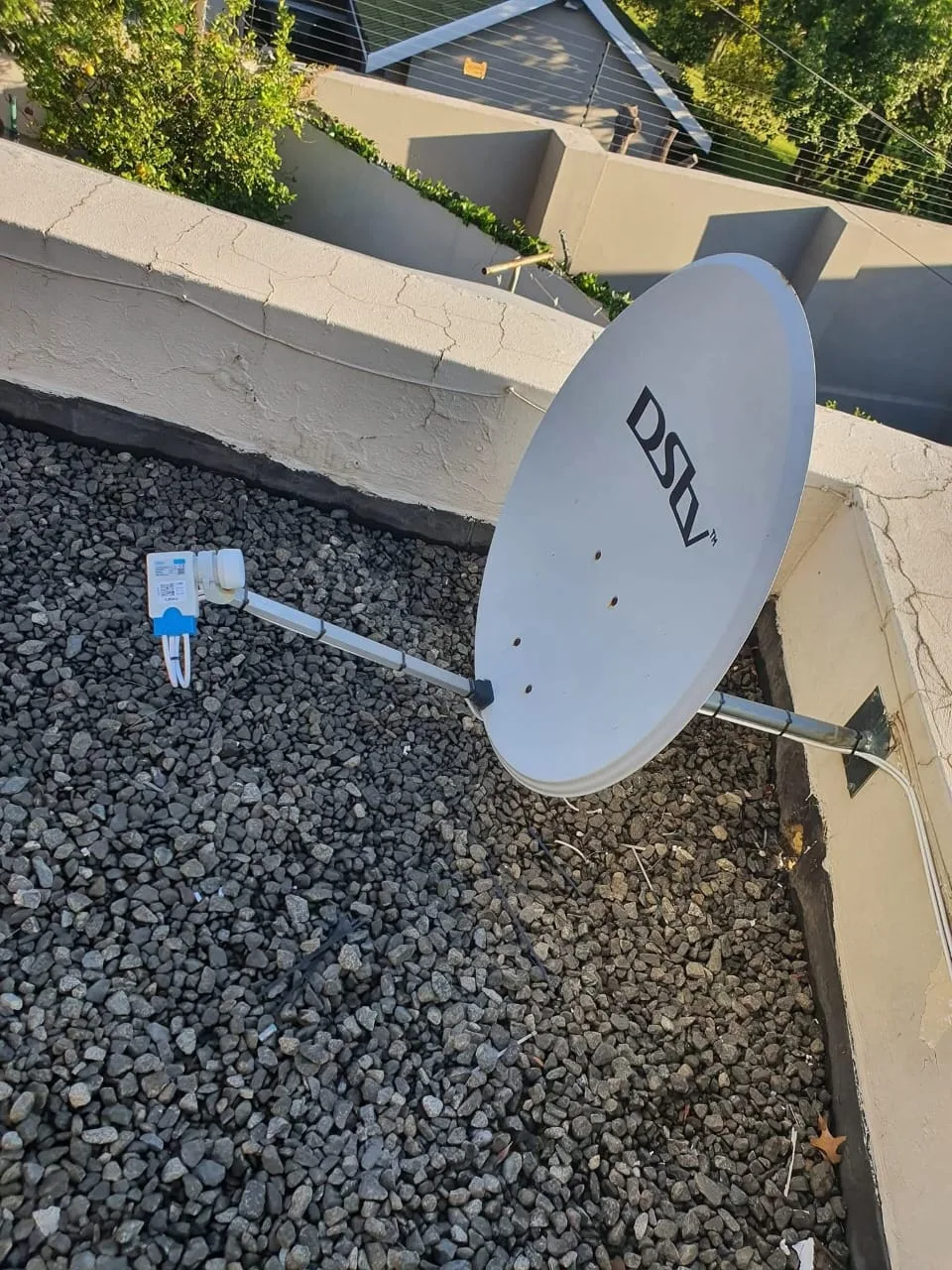 DSTV satellite dish installed on a gravel flat-roof surface